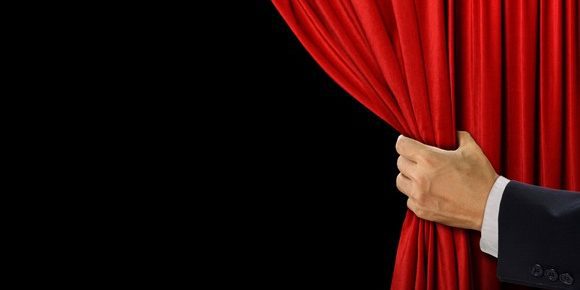 man pulling back a curtain to reveal whats behind it